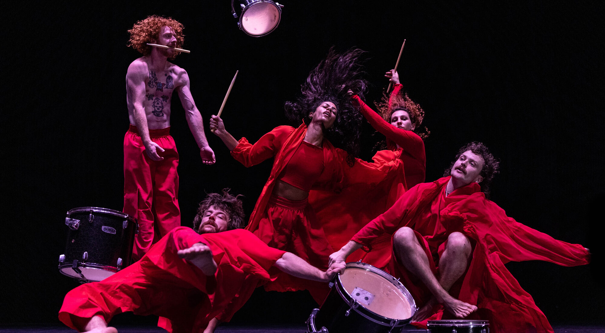 Drummers wearing red costumes. They are performing.