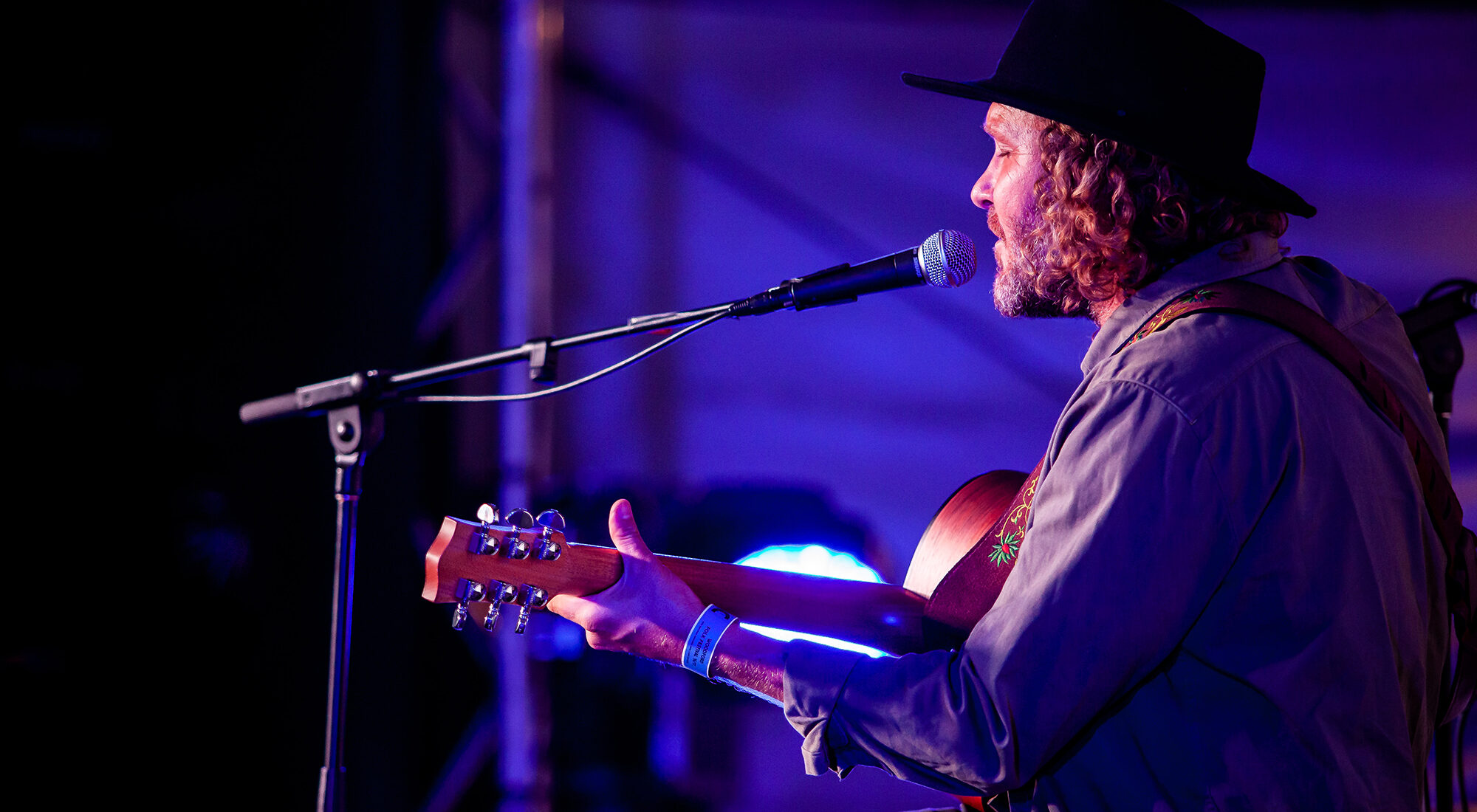 A man singing into a microphone playing a guitar.